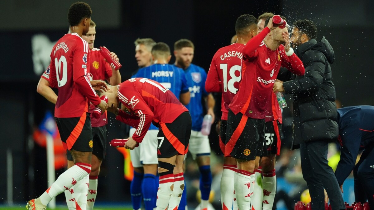 Manchester United's Diogo Dalot splashes his face with water during the English Premier League match against Ipswich Town as gaffer Ruben Amorim talks to his team | AP