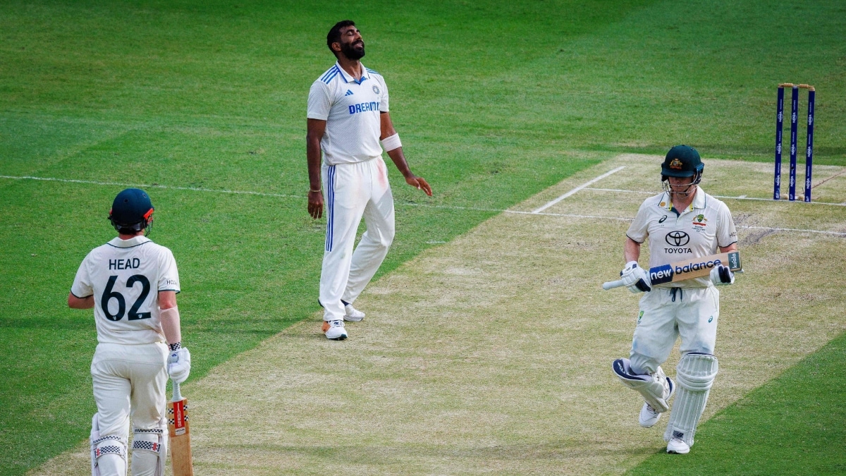 India's Jasprit Bumrah reacts after Australia's Travis Head (L) scores another boundary as Steve Smith (R) looks on | AFP