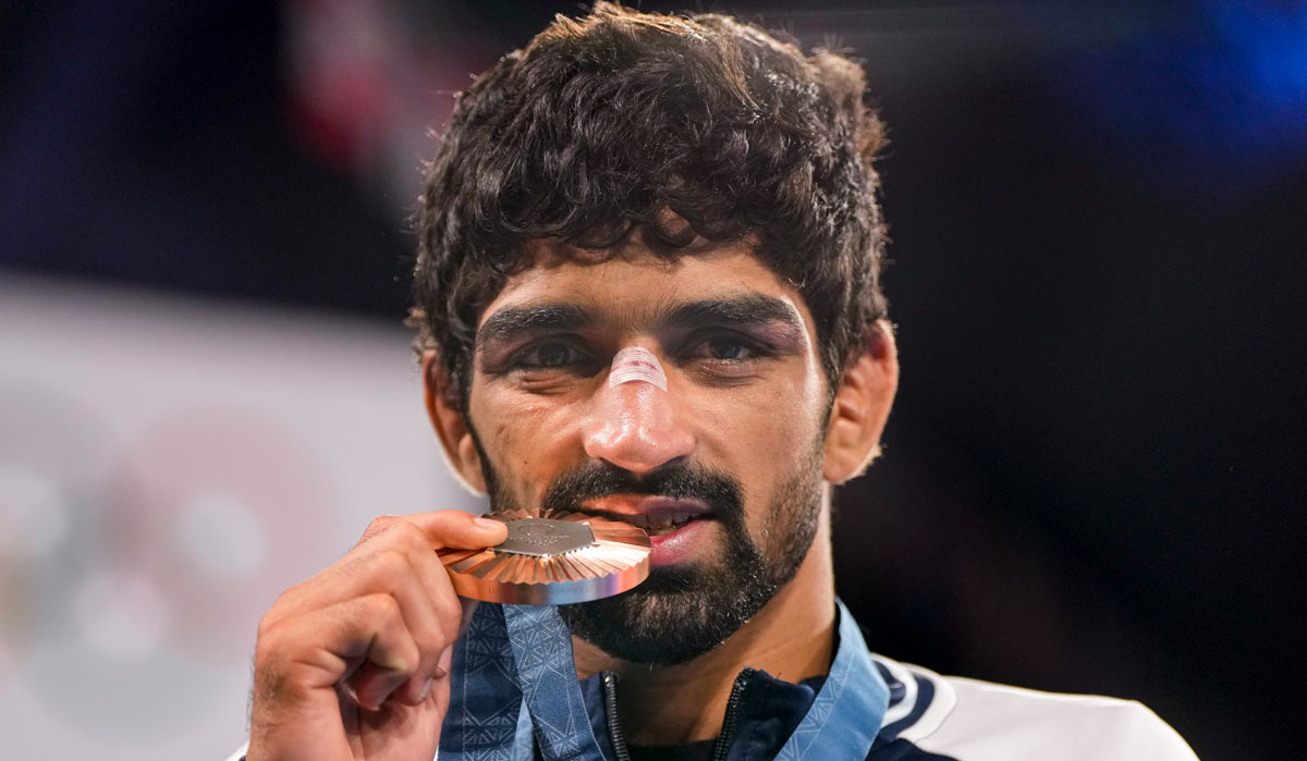 Bronze medalist Aman Sehrawat poses for photos at the podium during the victory ceremony | PTI
