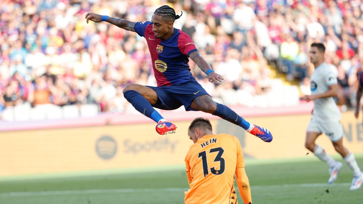 Barcelona's Raphinha jumps over Valladolid's goalkeeper Karl Hein | AP