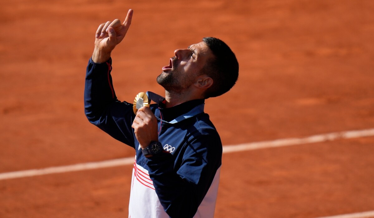Serbia's Novak Djokovic gestures while holding his gold medal | AP