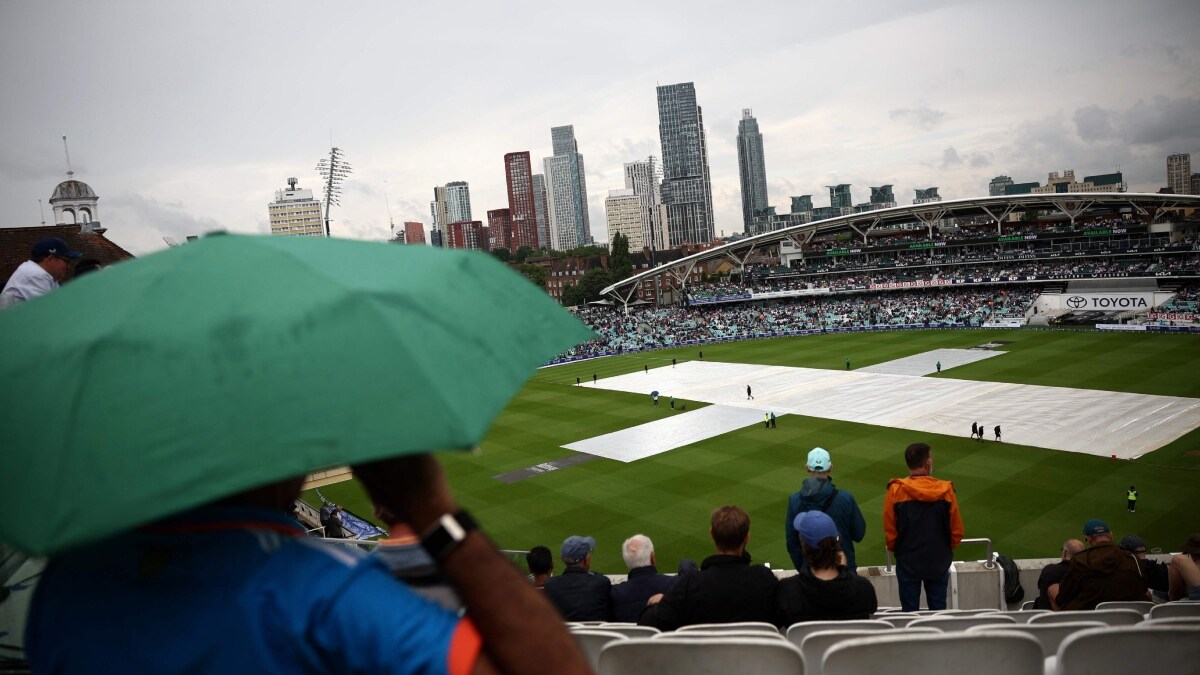 Spectators look on as rain stops play on the first day of the fifth Test cricket match between England and India at The Oval in London | AFP
