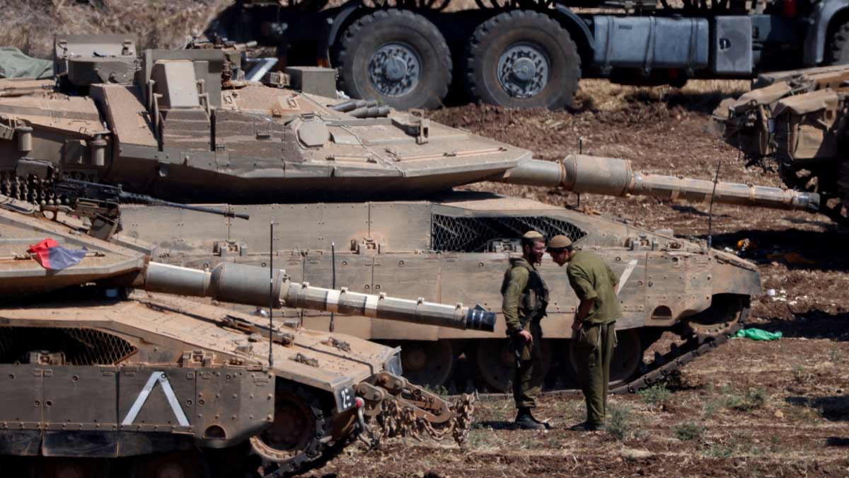 Israeli members of the military stand next to armoured vehicles, amid cross-border hostilities between Hezbollah and Israel, in northern Israel | Reuters
