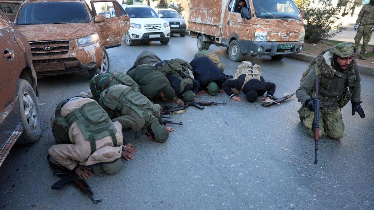 Hayat Tahrir al-Sham (HTS) fighters kneel to pray in a street in Aleppo | AFP