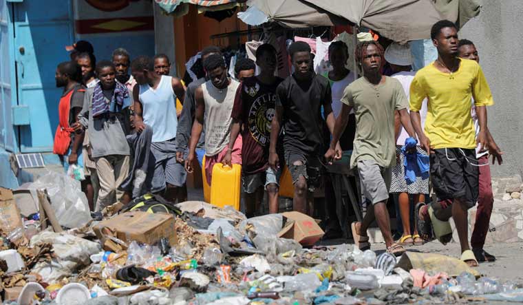 People wait to collect water in containers along a street after Haiti's Prime Minister Ariel Henry pledged to step down following months of escalating gang violence, in Port-au-Prince in Haiti | PTI