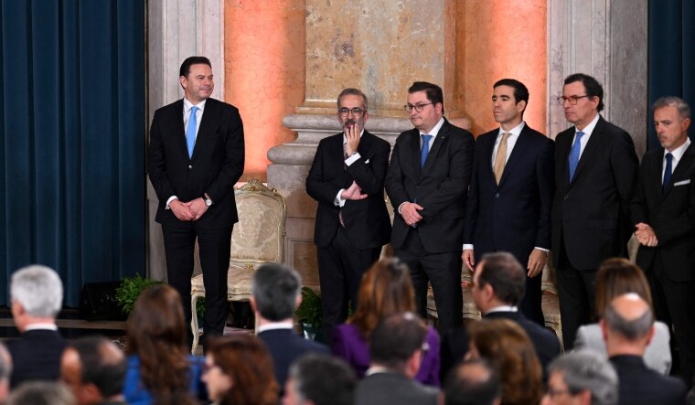 Portuguese new Prime Minister Luis Montenegro (L) stands next to his governments ministers during the swearing-in ceremony | AFP