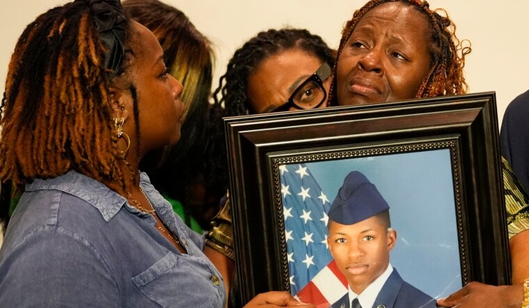 Chantemekki Fortson, mother of Roger Fortson, a U.S. Air Force senior airman, is comforted by family as she holds a photo of her son during a news conference | AP