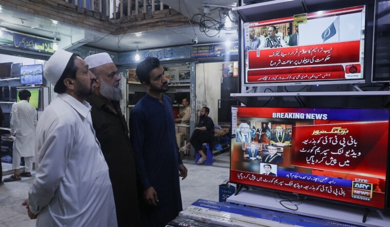 Men watch television screens as they wait to see the appearance of the jailed Pakistan's former Prime Minister Imran Khan, expected to be streamed live during a video proceeding of the Supreme Court of Pakistan | Reuters