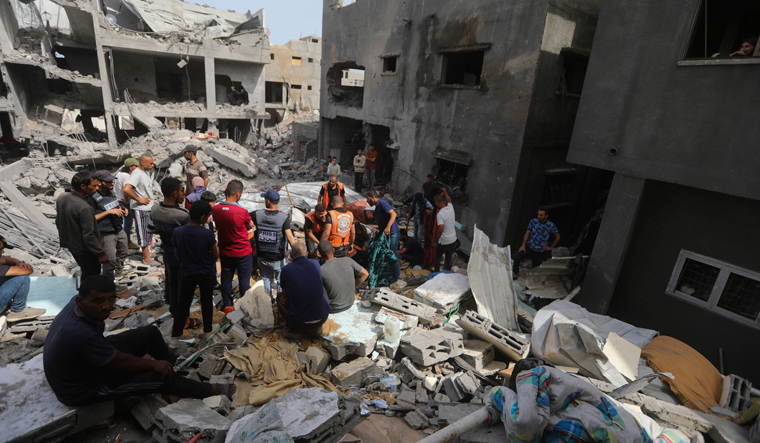 Palestinians look at the destruction after an Israeli strike on a residential building in Nuseirat Refugee Camp, Gaza Strip | AP