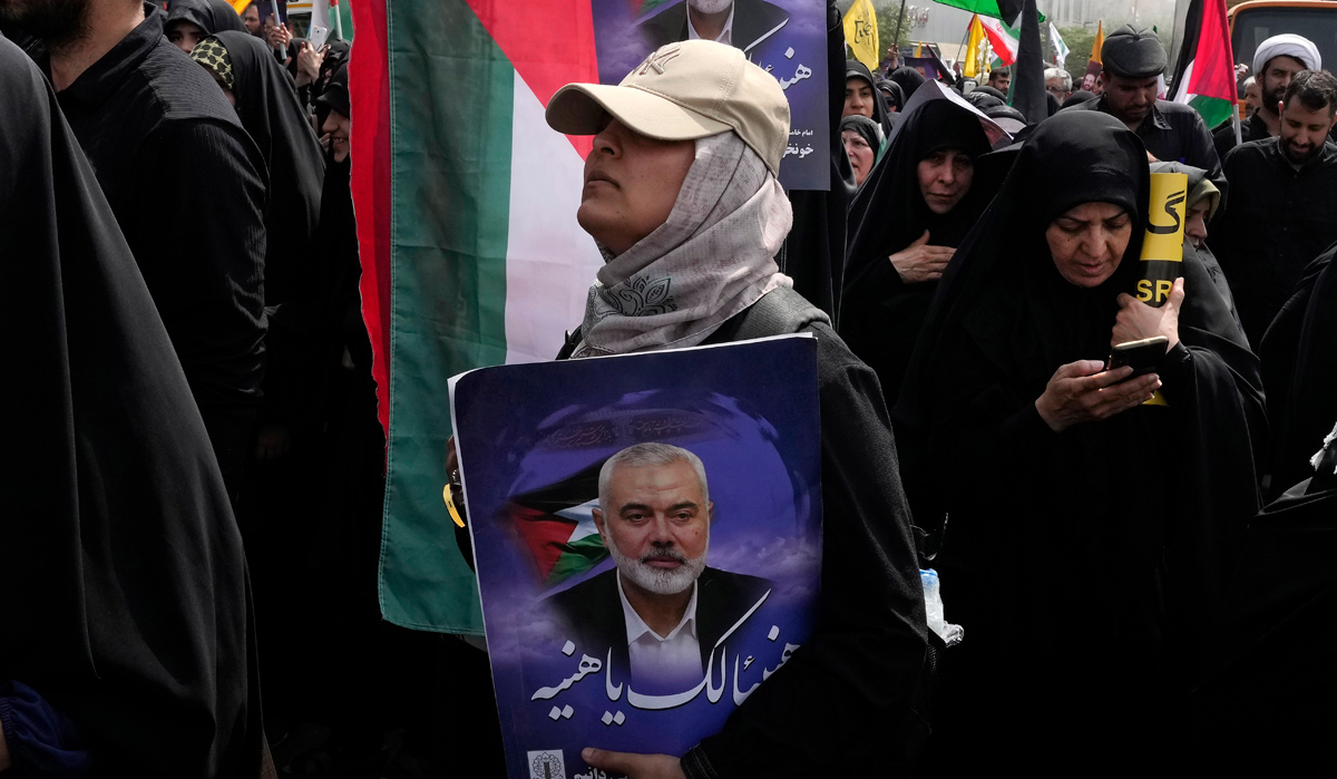 An Iranian woman holds a poster of Hamas leader Ismail Haniyeh during his funeral ceremony in Tehran | AP