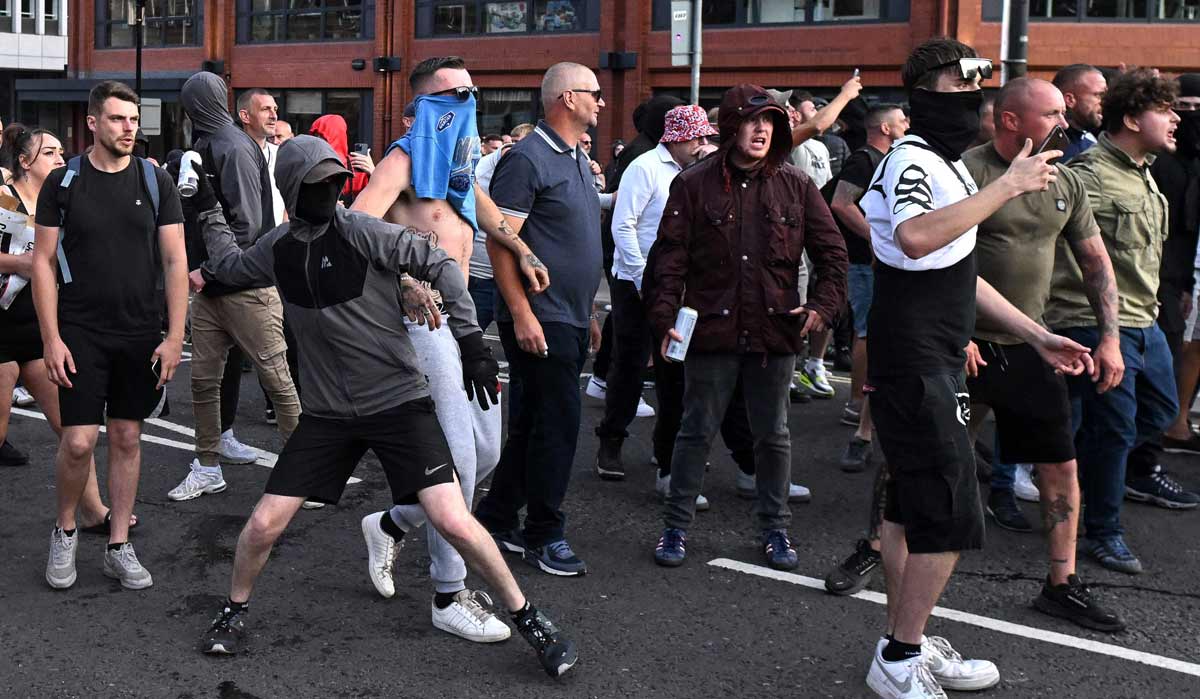A masked protester throws a can of beer towards riot police in Bristol | AFP
