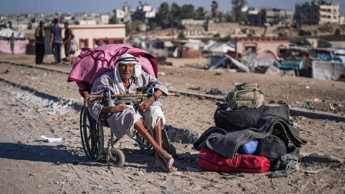 An elderly Palestinian man in a wheelchair waits with his belongings to flee the Khan Younis area of the Gaza Strip | AP