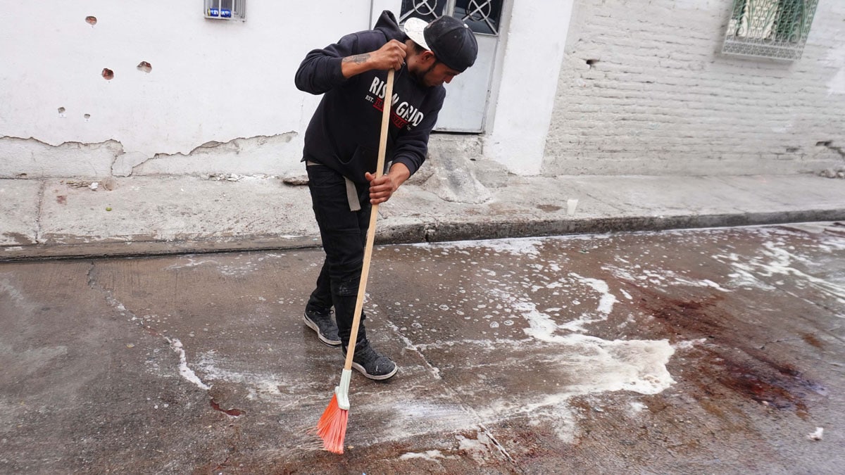 A man sweeps stains of blood after a shooting at the Barrio Nuevo neighbourhood in Irapuato, Guanajuato state, Mexico, on June 25, 2025. Gunmen killed 10 people including children in an attack on a house in a central Mexican city plagued by gang-related violence, authorities said Wednesday. (Photo by MARIO ARMAS / AFP)