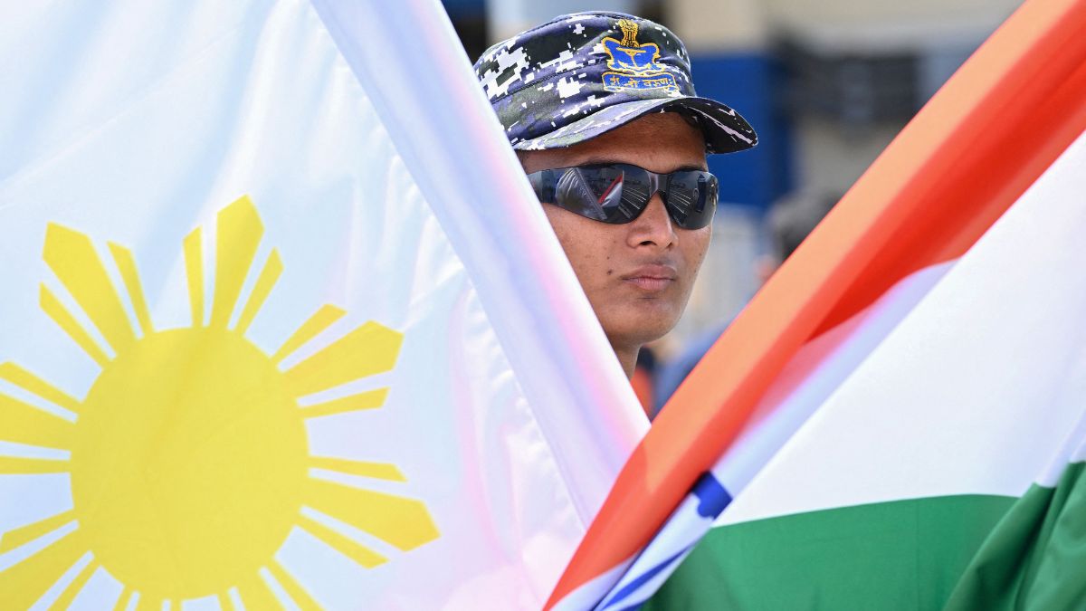 An Indian Navy sailor stands with Philippine and Indian flags at the international port of Manila | AFP 