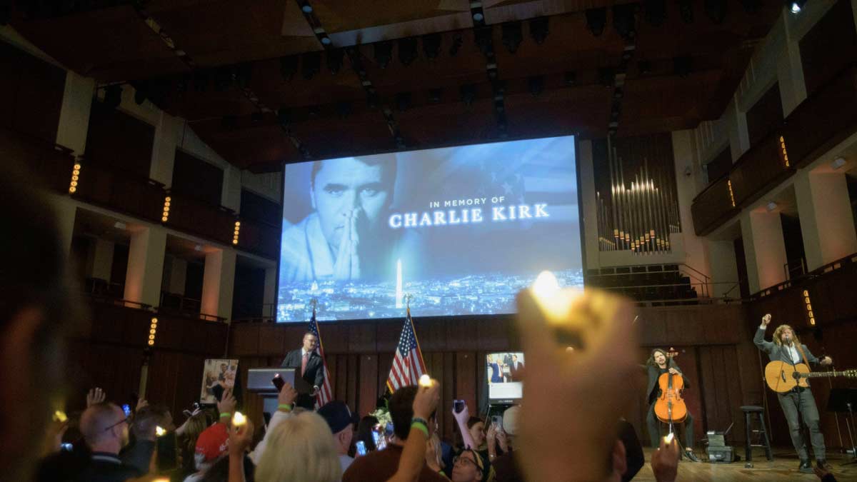 People hold candles and sing during a memorial and prayer vigil for Charlie Kirk at the John F. Kennedy Memorial Center for the Performing Arts | AP