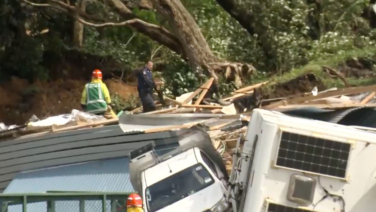 In this image from a video, a police officer with dog searches people near the site of a landslide at the base of Mount Maunganui on New Zealand's North Island | AP