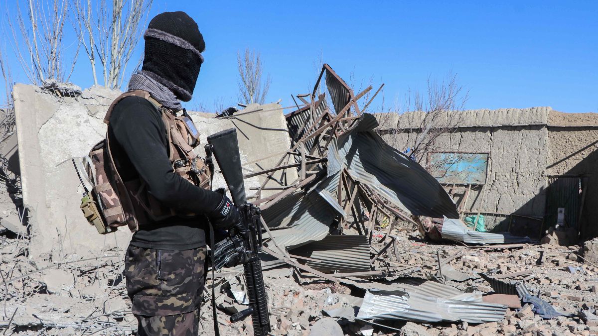 A Taliban security personnel stands next to the debris of houses destroyed during an overnight Pakistani airstrike at the Balish village in Urgun district, Paktika Province, on February 22, 2026 | AFP
