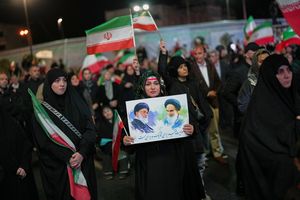 A woman holds a poster of Ayatollah Ali Khamenei (left) and Ayatollah Ruhollah Khomeini in Tehran | AP