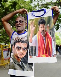 A TVK worker holding a shirt with Vijay’s photograph | AP
